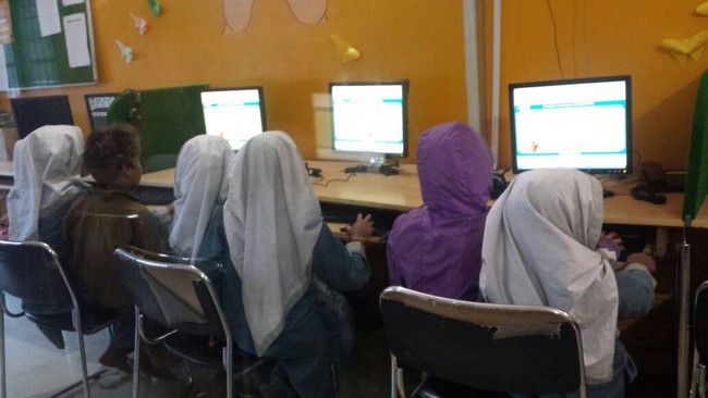 Kids and females engaged in tech- enabled resources at learning kiosk